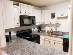 a kitchen with white cabinets and a black stove at SPECIAL RATE Golfer's Paradise & 10 Minutes to Rocky Top Sports in Gatlinburg