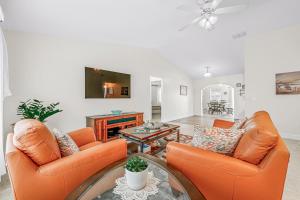 a living room with two orange chairs and a tv at Beautiful Home Away From Home in Royal Palm Beach
