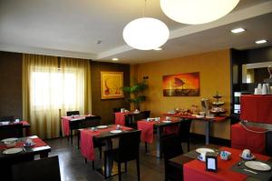 a restaurant with tables and chairs with red table cloth at Hotel Fly in Casoria