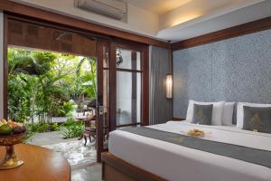 a bedroom with a large bed and a patio at The Alantara Sanur in Sanur