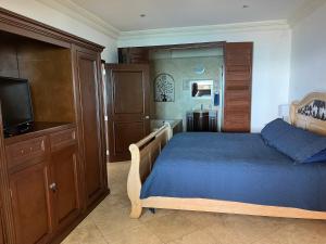 1 dormitorio con 1 cama con colcha azul y TV en Oceanview Condo Resort. Las Olas Grand Rosarito, en Divisadero
