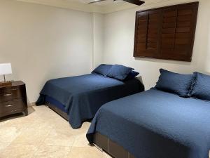 1 dormitorio con 2 camas con sábanas azules y armario en Oceanview Condo Resort. Las Olas Grand Rosarito, en Divisadero
