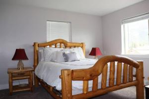 1 dormitorio con 1 cama de madera y 2 lámparas en Rustic Range Retreat - Glacier Park Getaway en Columbia Falls