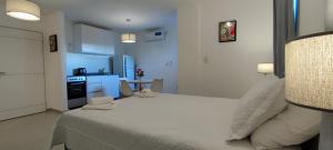 a bedroom with a white bed and a kitchen at Sttanze Giardino in Posadas