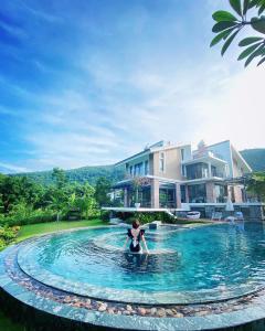 Eine Frau im Wasser in einem Pool vor einem Haus. in der Unterkunft Nam Casa Sân Golf Tam Đảo Venuestay in Tam Ðảo