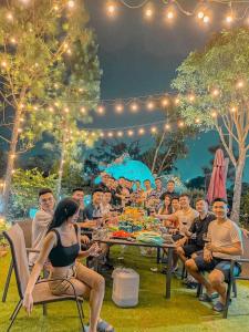 Un gruppo di persone seduti intorno a un tavolo ad una festa di Nam Casa Sân Golf Tam Đảo Venuestay a Tam Ðảo