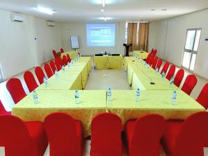 a conference room with tables and red chairs and a screen at Juba Landmark Hotel in Juba