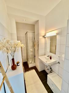 a white bathroom with a sink and a shower at Wohnen über den Dächern von Bregenz in Bregenz