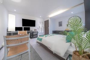 1 dormitorio blanco con 1 cama y TV en BY THS Shine Hotel Siheung Wolgot, en Siheung