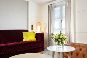 ein Wohnzimmer mit einem Sofa und einem Tisch mit einer Blumenvase in der Unterkunft Hotel Opéra Richepanse in Paris