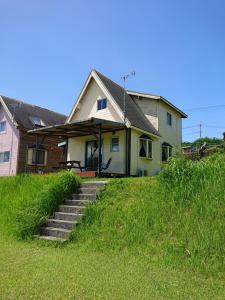 a house with stairs in the grass in front of it at Garden Beach House in Motobu