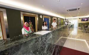 três mulheres em pé num balcão no átrio de um hotel em One Avenue Hotel em Petaling Jaya
