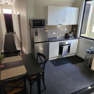 a kitchen with a refrigerator and a table and a microwave at City Villa 41 Blende st Broken Hill NSW 2880 in Broken Hill