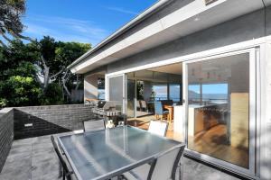 a glass table on the balcony of a house at Architectural Design on the Beach in Winda Woppa