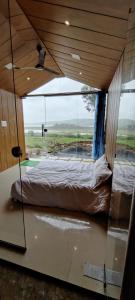 a bedroom with a bed and a large window at Pawna Resort in Lonavala