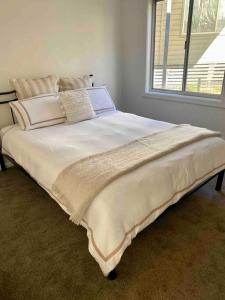 a large white bed in a room with a window at Clancy's Cottage -Talbingo in Talbingo