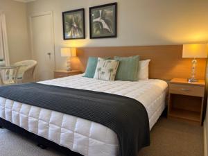 The Arabella North Coast في Wollongbar: غرفة نوم بسرير كبير مع طاولتين ومصباحين