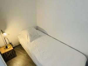 a small bedroom with a white bed and a lamp at Appartement Moderne 5 Couchages avec Parking et Piscine - FR-1-748-8 in Canet-en-Roussillon +18 photos