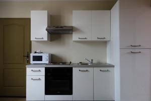 a kitchen with white cabinets and a microwave at Adéloïa Cottage in Fauverney