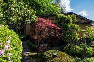 a house with trees and flowers in front of it at 料理の宿　伊豆の花 in Ito