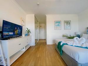 a bedroom with a bed and a flat screen tv at Charming Burleigh Studio in Gold Coast