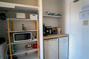 a small kitchen with a microwave and a refrigerator at Charming Burleigh Studio in Gold Coast