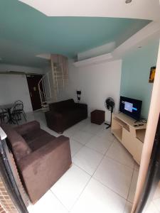 a living room with a couch and a tv at Apartamento dúplex em frente ao mar de Pajuçara in Maceió