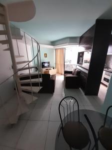 a living room with a staircase and a couch at Apartamento dúplex em frente ao mar de Pajuçara in Maceió