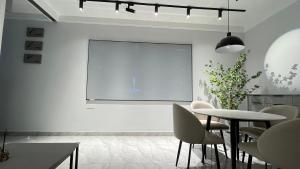 une chambre blanche avec une table et un écran de projection dans l'établissement Xingyu Apartment - Tianhe Road, à Canton