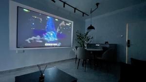 un salon avec un grand écran de projection sur le mur dans l'établissement Xingyu Apartment - Tianhe Road, à Canton