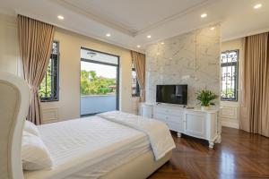 a bedroom with a bed and a flat screen tv at VILLA PARK in Kinh Dinh