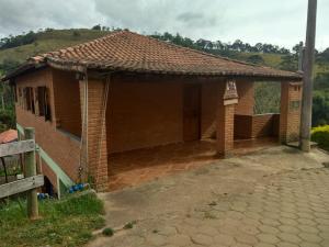 uma pequena casa de tijolos com um grande pátio em Chalé Canto Da Vila Ibitipoca em Conceição do Ibitipoca