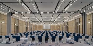 Crowne Plaza Hangzhou Riverside, an IHG Hotel في هانغتشو: غرفة كبيرة مع طاولات زرقاء وكراسي بيضاء
