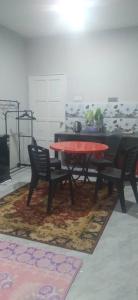 uma sala de jantar com uma mesa e cadeiras num tapete em Ema roomstay em Jementah
