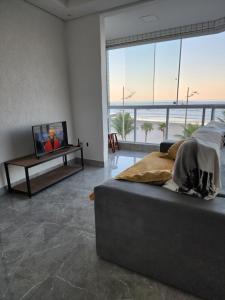 a bedroom with a bed and a tv on a table at Frente mar, pé na areia !! in Praia Grande