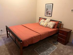 1 cama con sábanas y almohadas de color naranja en un dormitorio en Private self check in home, en Alice Springs