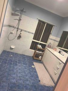 baño con ducha y suelo de baldosa azul. en Private self check in home, en Alice Springs