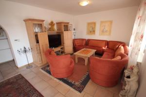 ein Wohnzimmer mit orangefarbenen Stühlen und einem Fernseher in der Unterkunft Apartment Maris with nice sea view in Ljubač