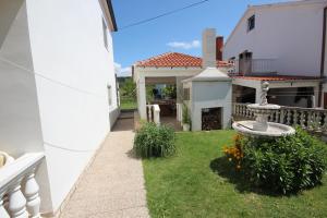 ein weißes Haus mit einem Garten mit Springbrunnen in der Unterkunft Apartment Maris with nice sea view in Ljubač