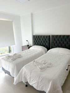 two beds in a bedroom with white sheets at Departamento Veneto Village - B in Villa Parque Siquiman