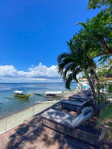 a beach with chairs and a boat in the water at Solitude Acacia Resort in Mabini