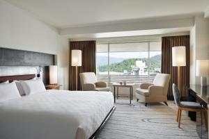 京都市にあるザ・プリンス 京都宝ヶ池、オートグラフ コレクションのベッドと大きな窓が備わるホテルルームです。