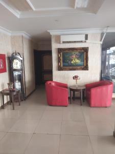 a lobby with red chairs and a table and a clock at دانات الخليج in Al Khobar