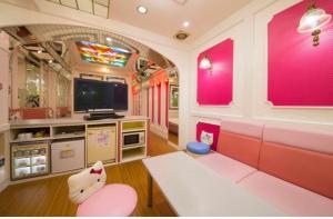 sala de estar con muebles de color rosa y TV en ホテル　アイネ　香芝店, en Kashiba
