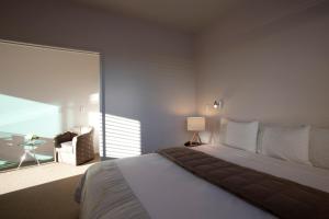 ein Schlafzimmer mit einem großen weißen Bett und einem Stuhl in der Unterkunft Broadway Motel & Miro Court Villas in Matamata