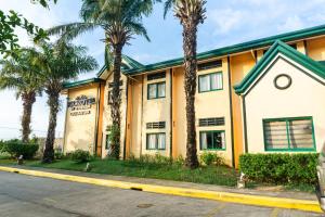 a building with palm trees in front of a street at Microtel by Wyndham Cabanatuan in Cabanatuan