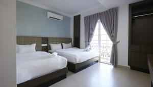 a hotel room with two beds and a window at Beryll Inn Cyberjaya Hotel in Cyberjaya
