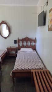 a bedroom with a wooden bed and a mirror at Estância Stela Pousada in Olímpia