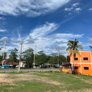 un bâtiment orange avec un palmier dans un champ dans l'établissement J2 INN, à Uttaradit