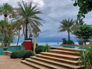 Karon Sea View Beach Apartment في شاطئ كارون: مجموعة من السلالم بجوار حمام سباحة مع أشجار النخيل.